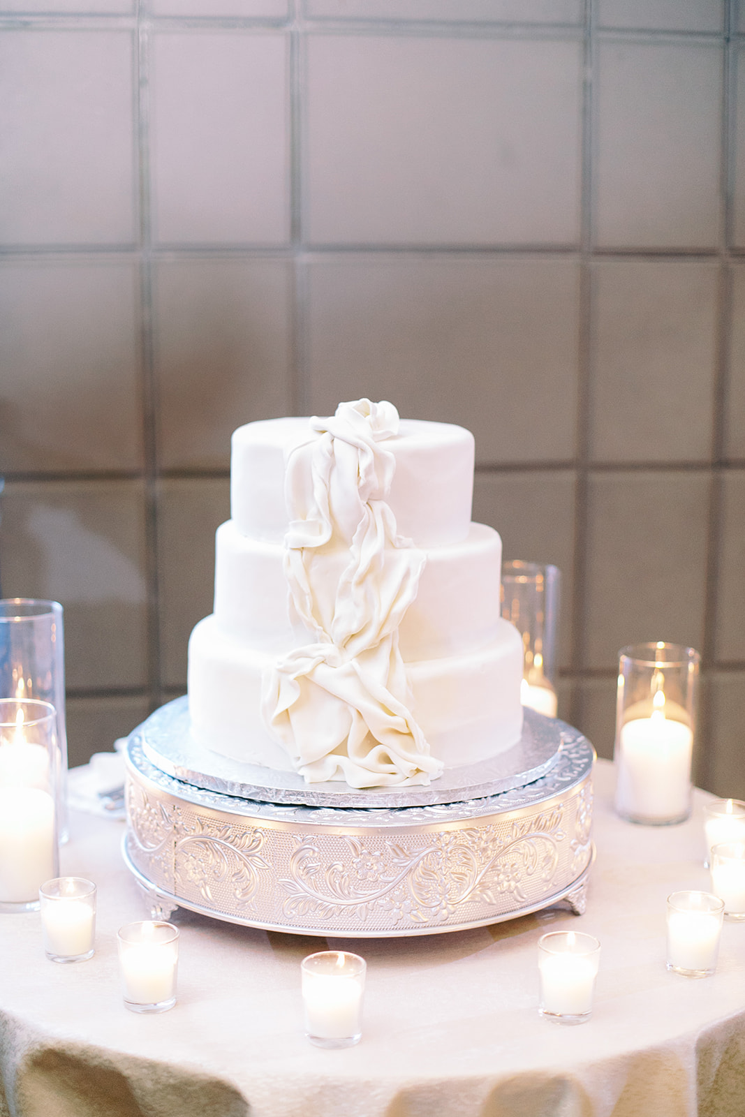 Three tiered white wedding cake with faux draping down side.