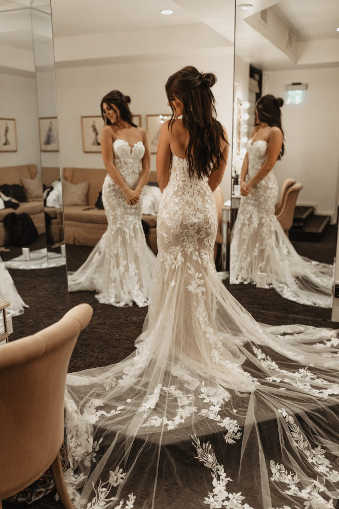 Bride looking to side in front of mirrors with wedding dress on.