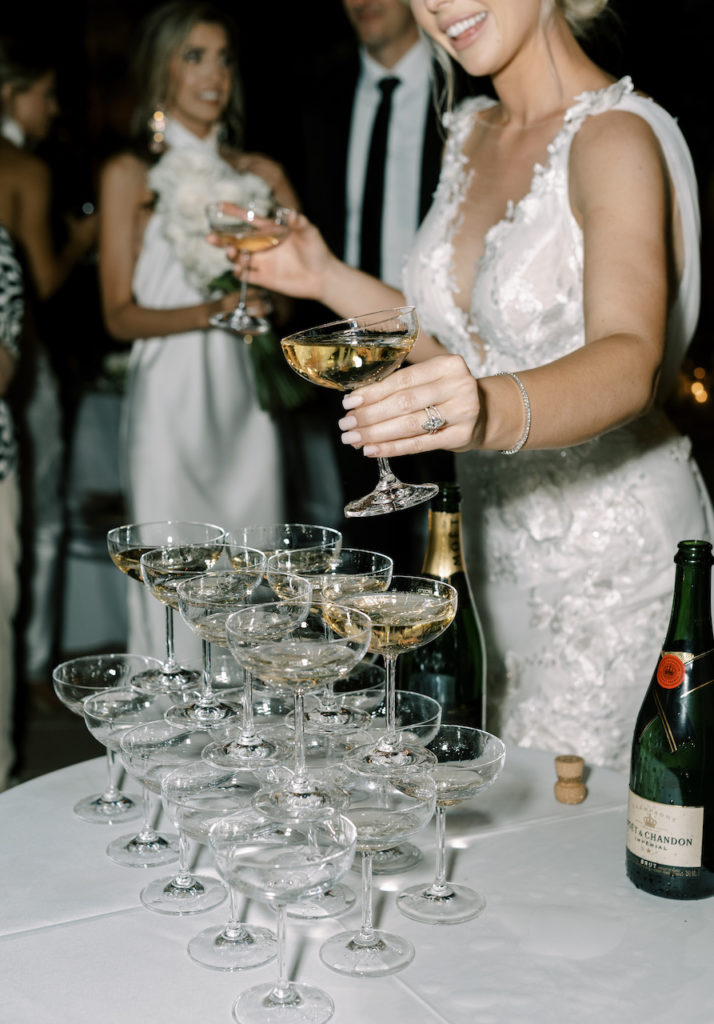 Bride building champagne tower of glasses.