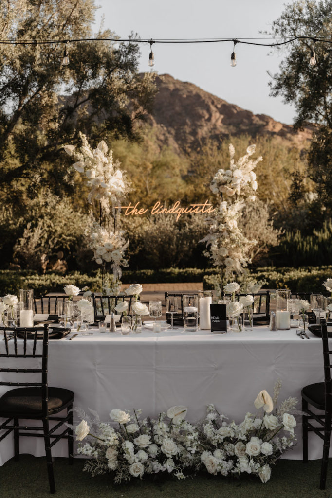 El Chorro outdoor wedding reception head table with candles and white floral designs.