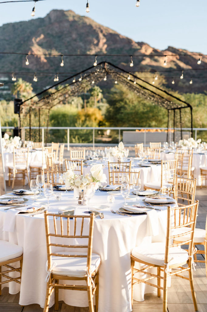 Outdoor wedding reception at Mountain Shadows with rounded guest tables and mountain in distance.