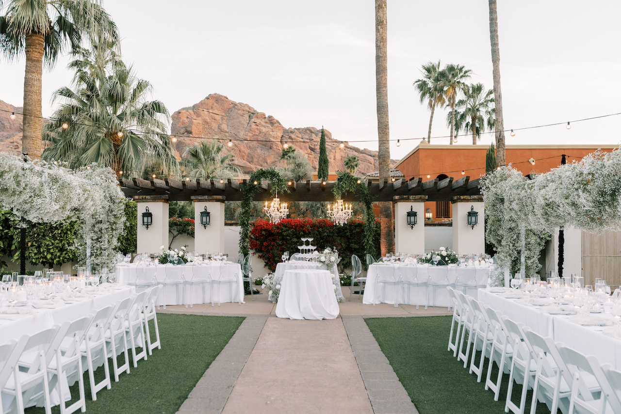 Outdoor wedding reception at Omni Montelucia with long white tables and center sweetheart table.