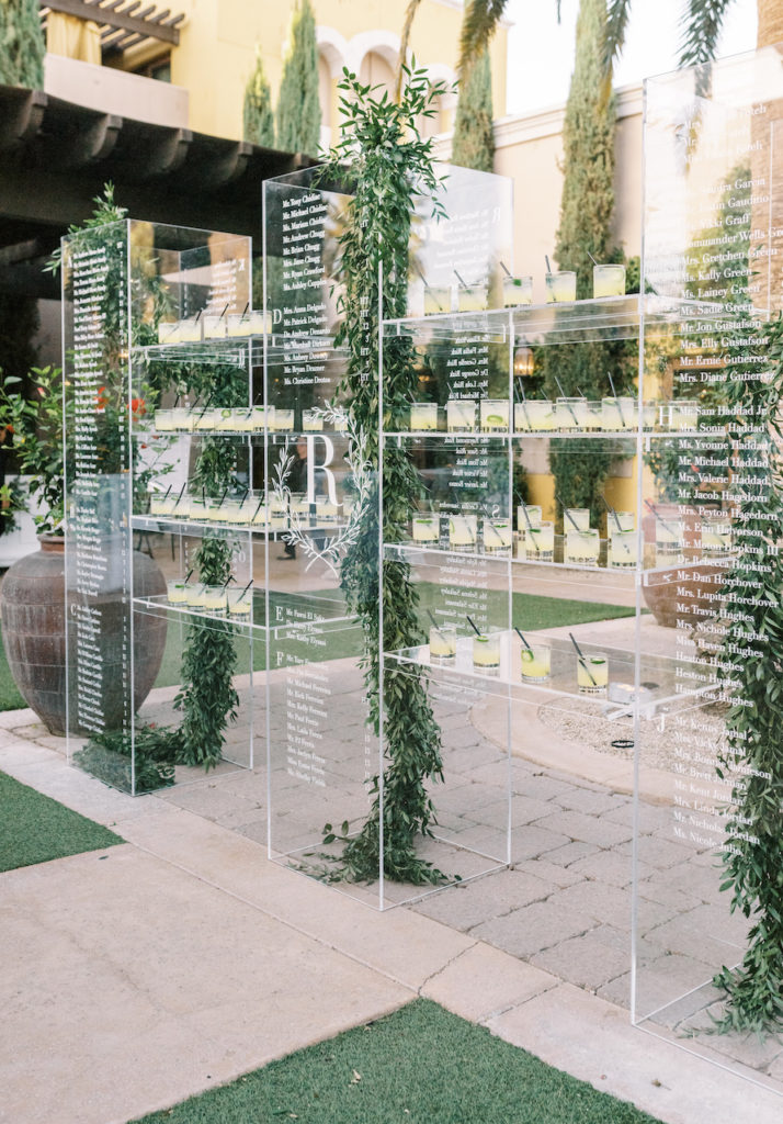 Custom clear acrylic wedding escort board with greenery installation.
