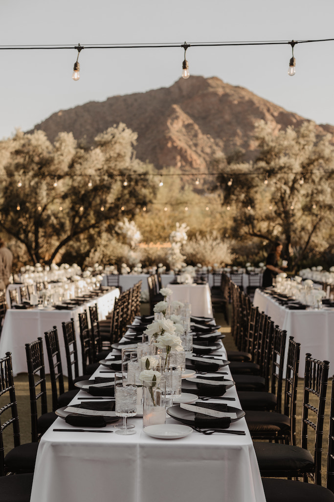 Outdoor wedding reception space at El Chorro with black plate place setting and white rose bud vases.