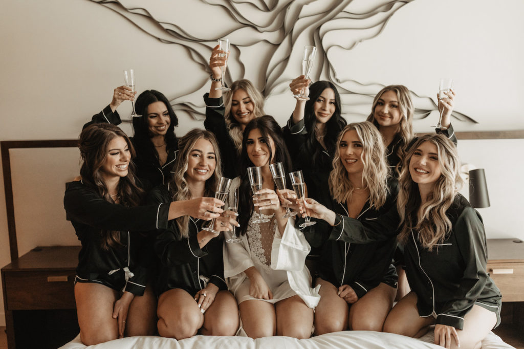 Bride and bridesmaids toasting champagne glasses while getting ready.