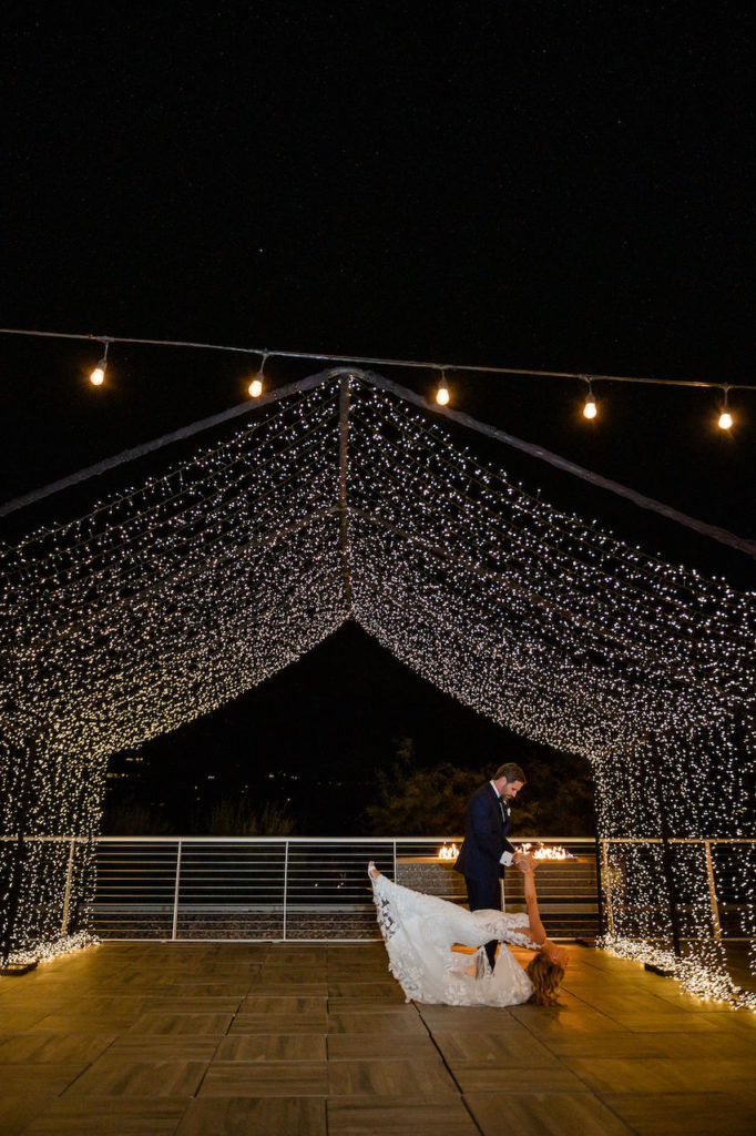 Bride and groom dancing in outdoor night wedding ceremony under canopied lights.