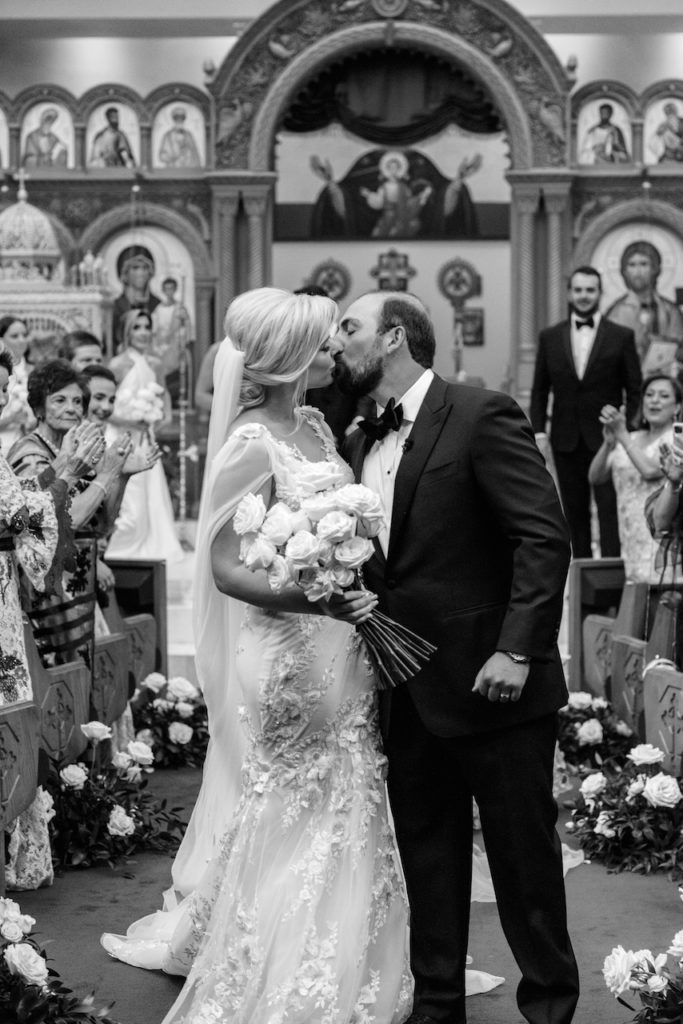 Bride and groom kissing at wedding ceremony in church.