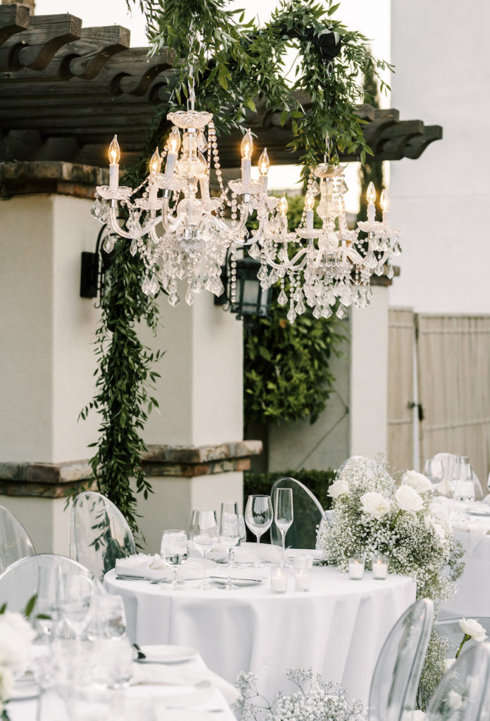 Hanging chandeliers over sweetheart table with greenery hooks.