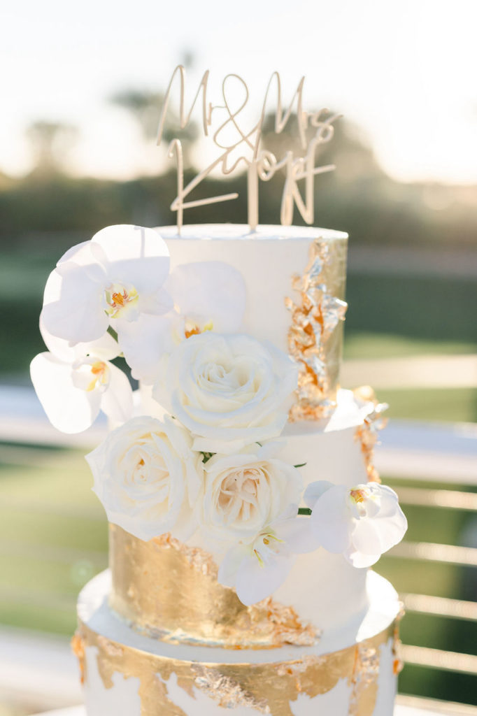 White wedding cake details with gold flake and white flowers.