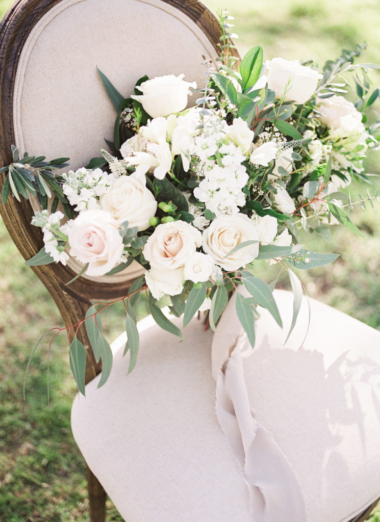 White floral bouquet sitting on a chair.