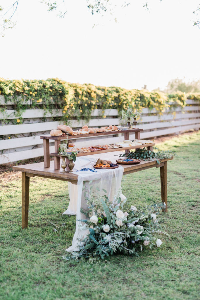Charcuterie table with ground floral in front of white flowers and greenery.
