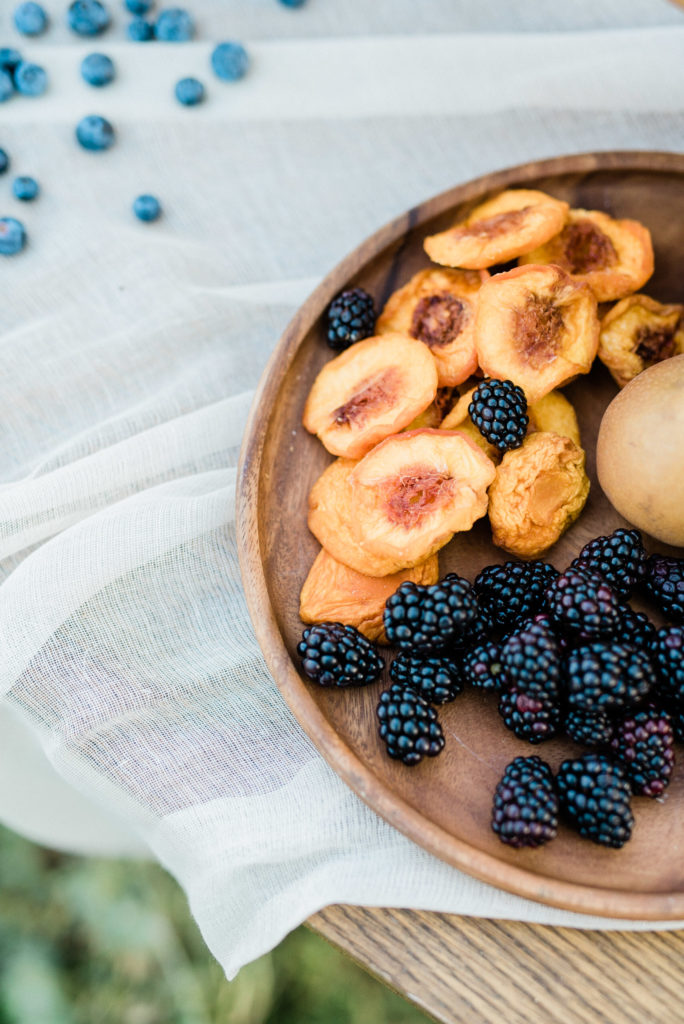 Dried peaches and blackberries on a wood plate.