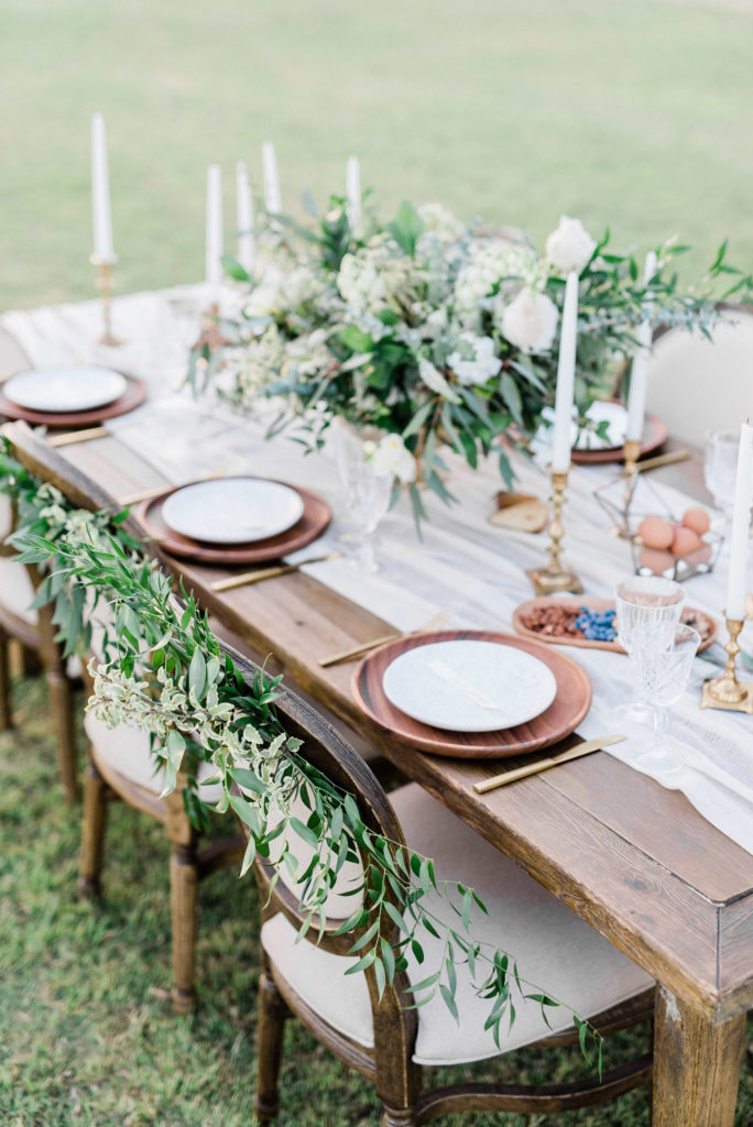 Set wedding reception table in grass yard with taper candles and centerpiece.