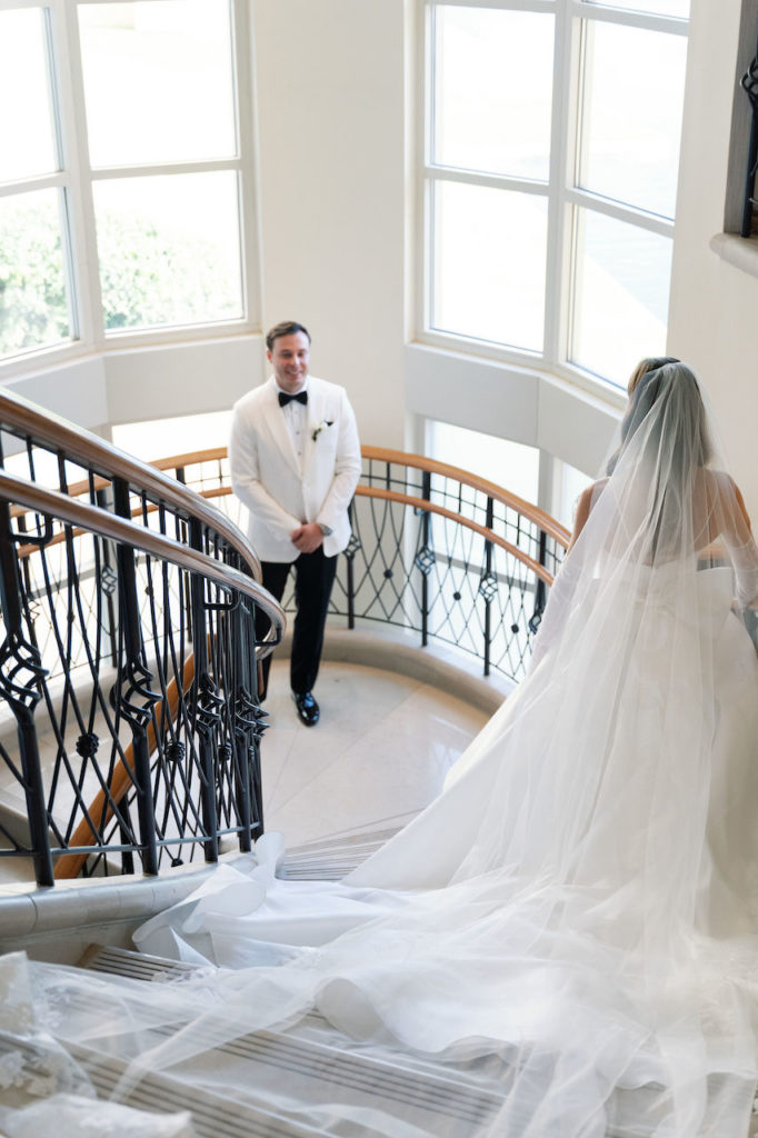 Bride entering down stairs with long veil for first look with groom.