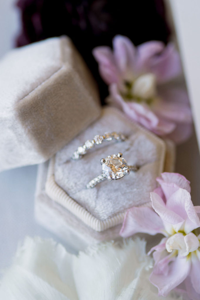 Bridal wedding rings in box with flowers around.