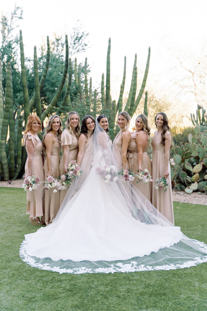 Bride standing with bridesmaids in a line, all holding bouquets.