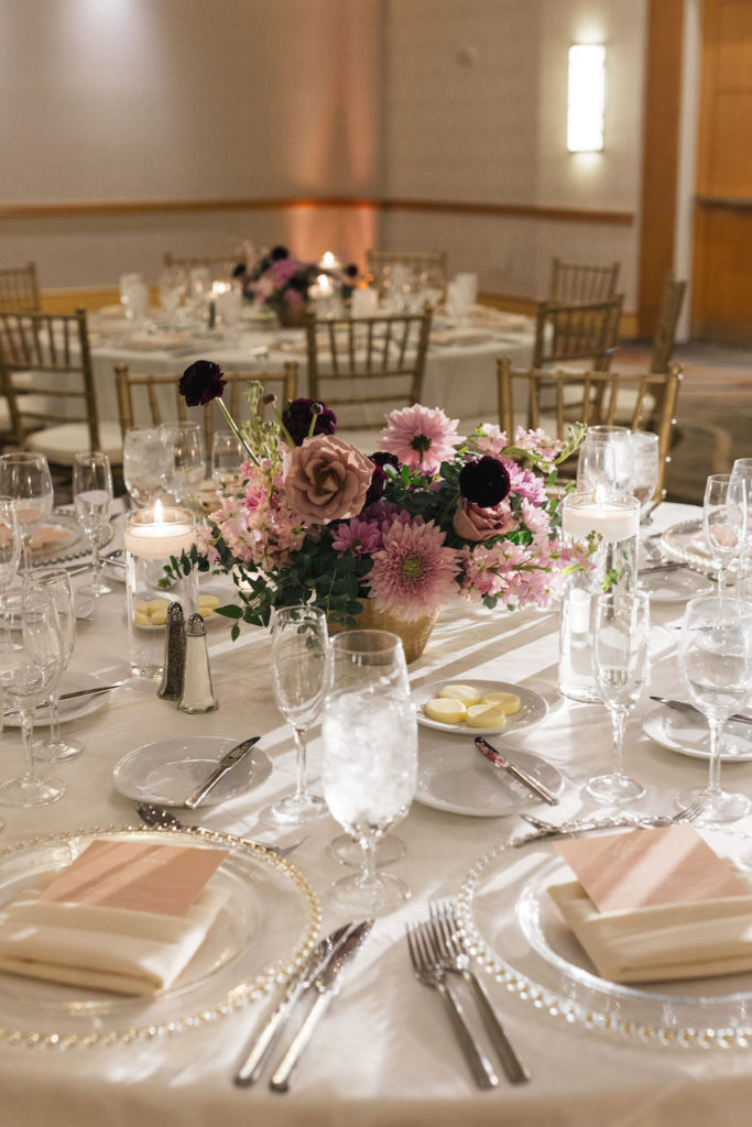 Mauve, pink, burgundy wedding reception centerpiece with candles.
