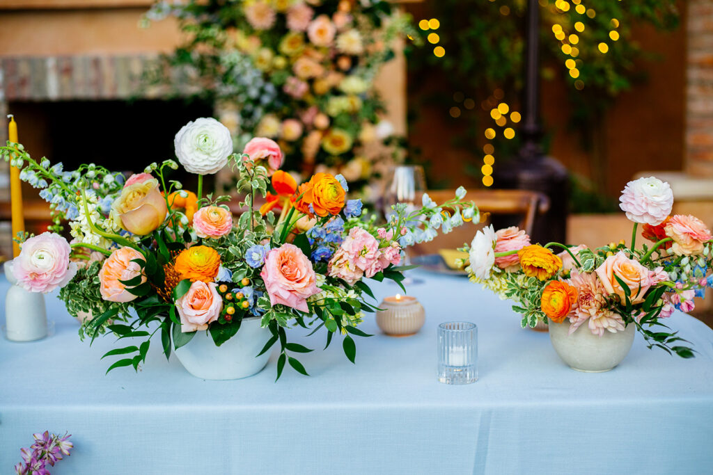 Table centerpieces in large and small sizes of pink, orange, and white.
