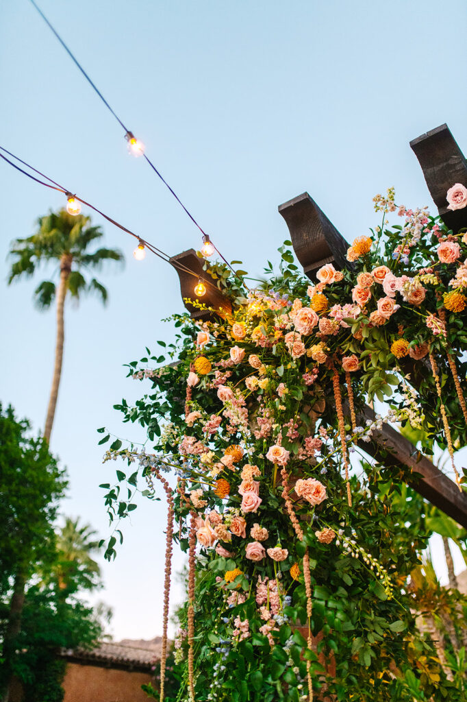 Overhead pergola floral installation of pink, white, and orange flowers at Royal Palms.