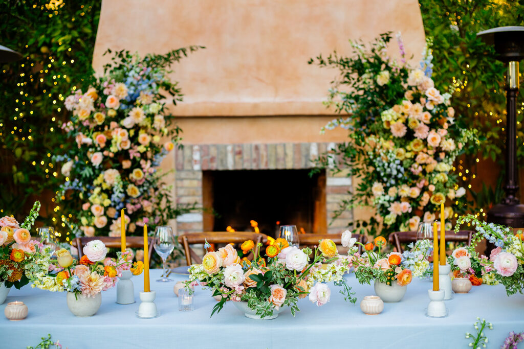 Wedding reception head table with lush floral decor and yellow taper candles.