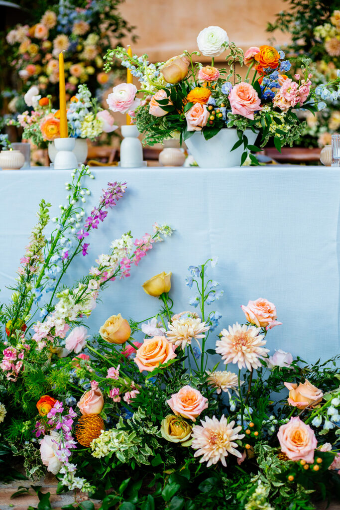 Head table at wedding reception with pink, orange and peach floral.