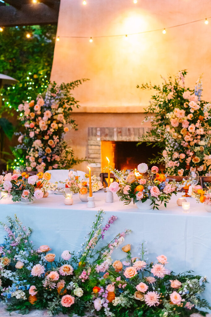 Lush reception head table flowers on table and ground.