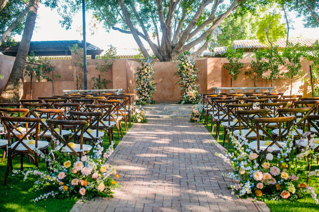 Outdoor wedding ceremony at Royal Palms with custom floral columns and aisle entrance and exit ground arrangements.