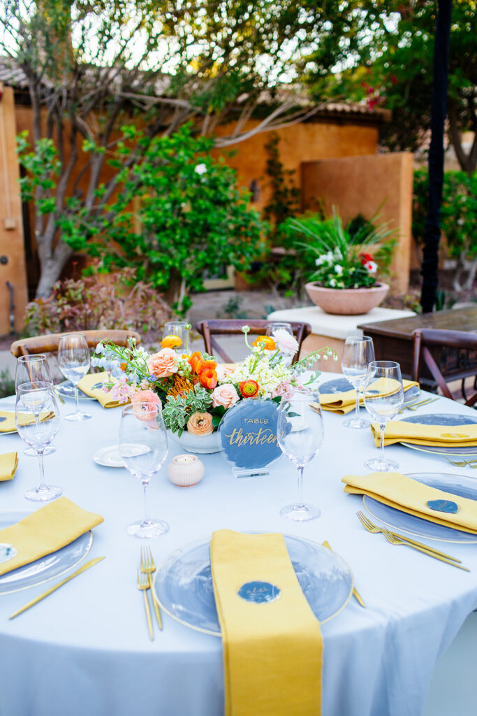 Round reception table with blue and yellow accents with floral centerpiece.