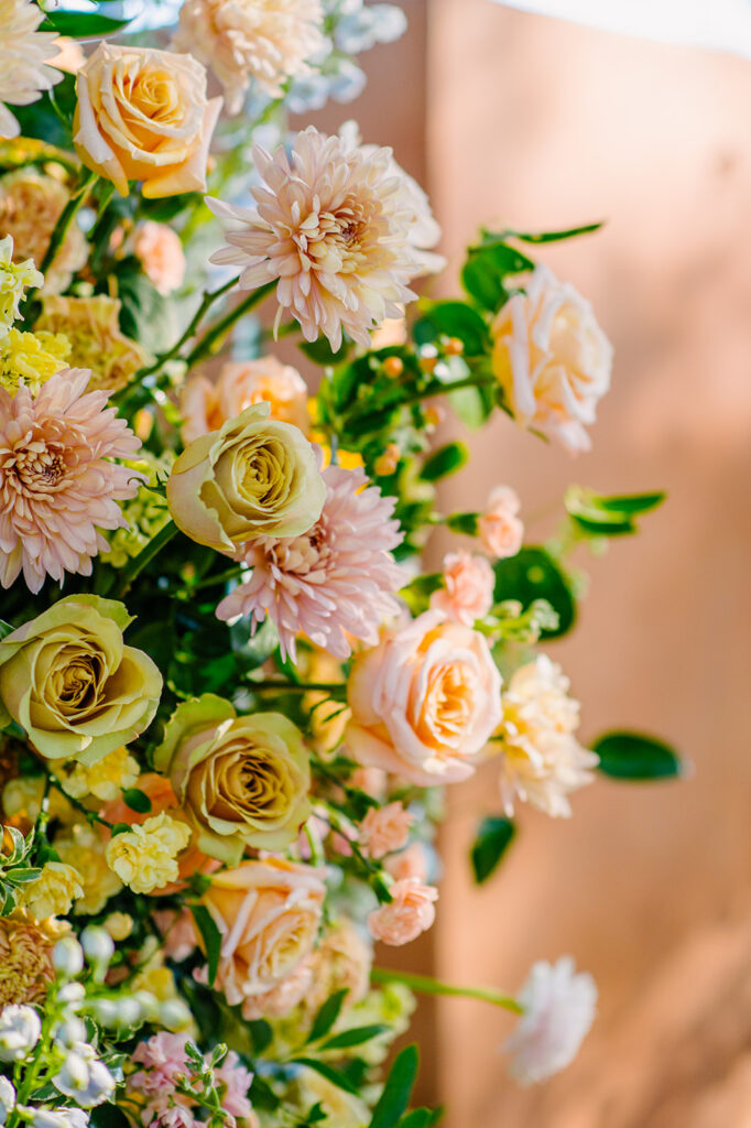 Close of up wedding ceremony floral arch flowers in pink, yellow, peach colors.