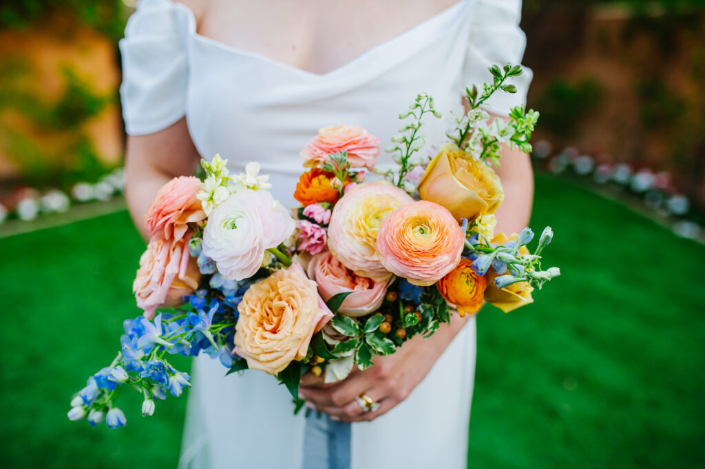Bride holding bouquet of bright colored flowers.