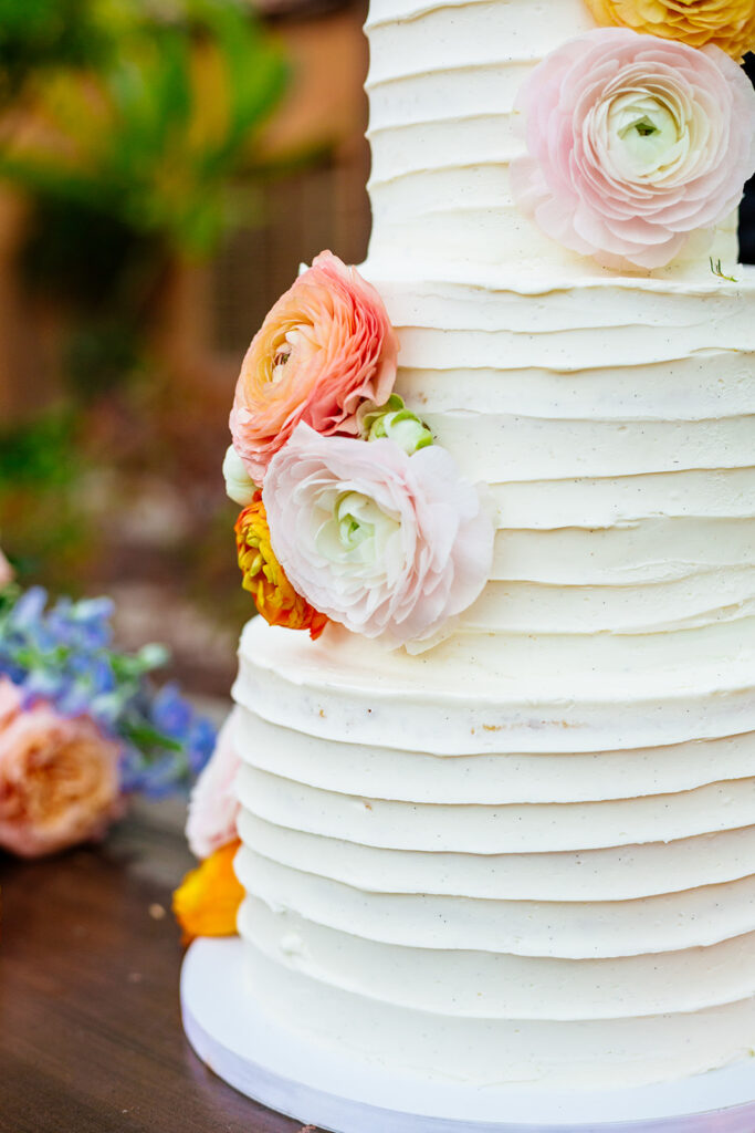 Close up of three tiered white wedding cake with flowers.