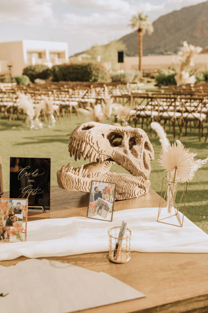 Wedding guestbook table with dinosaur skull and dried floral bud vases.