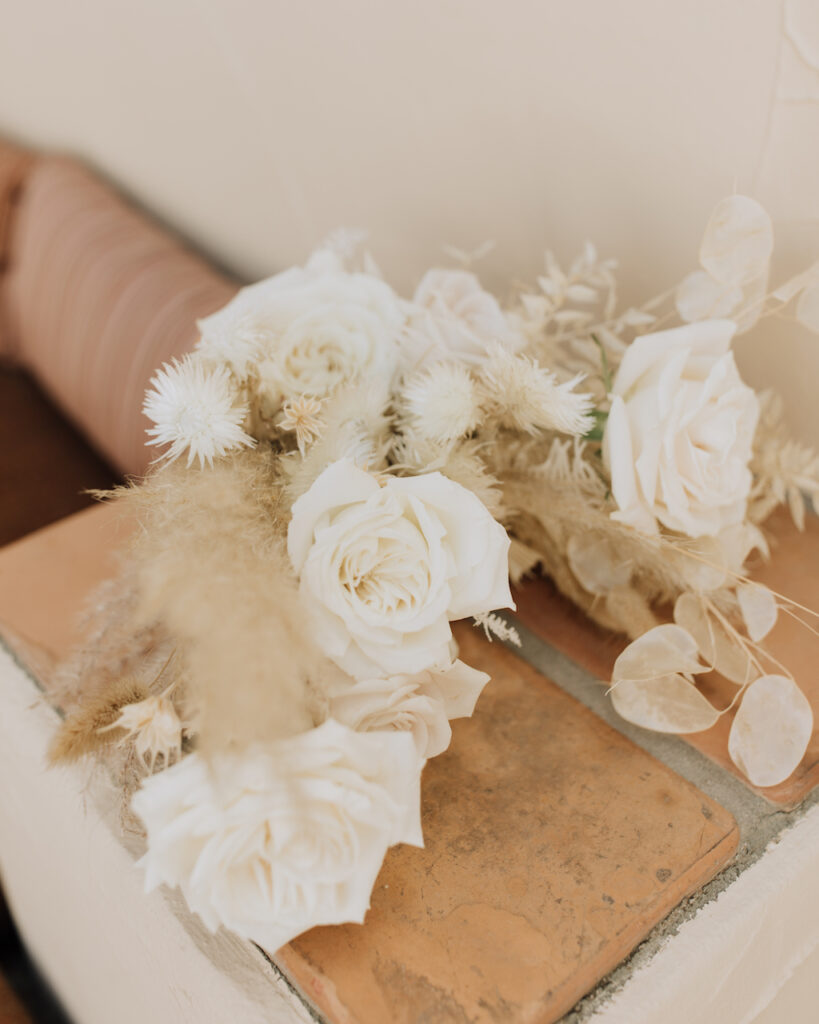 Bridal bouquet of dried floral elements, including pampas, and white roses.