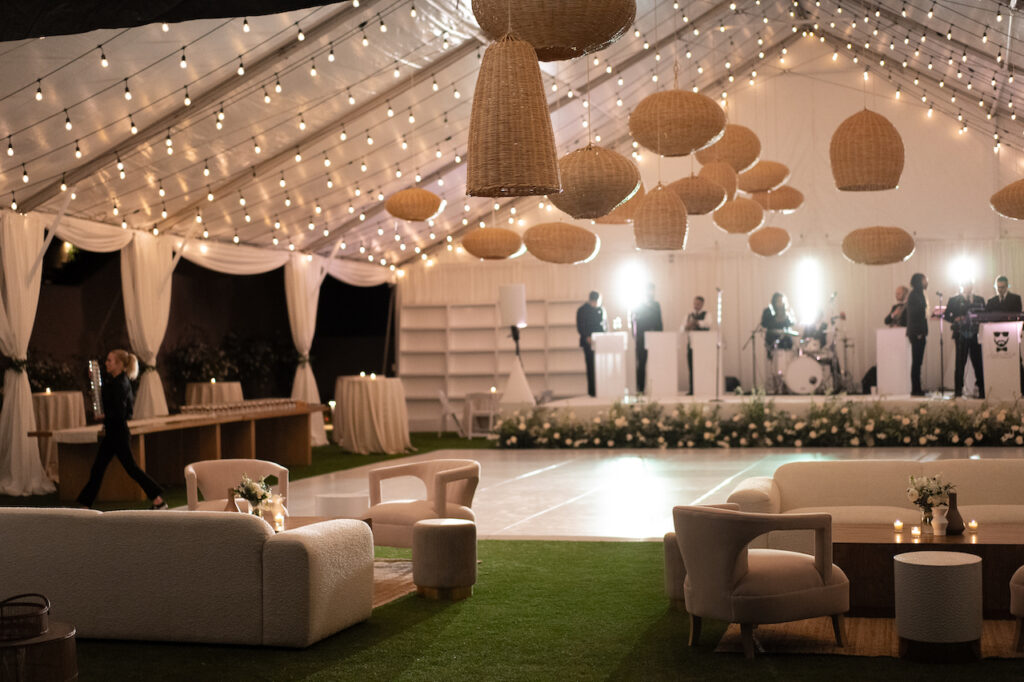 Wedding reception tent for dancing with live band, handing woven chandeliers and lounge seating areas.