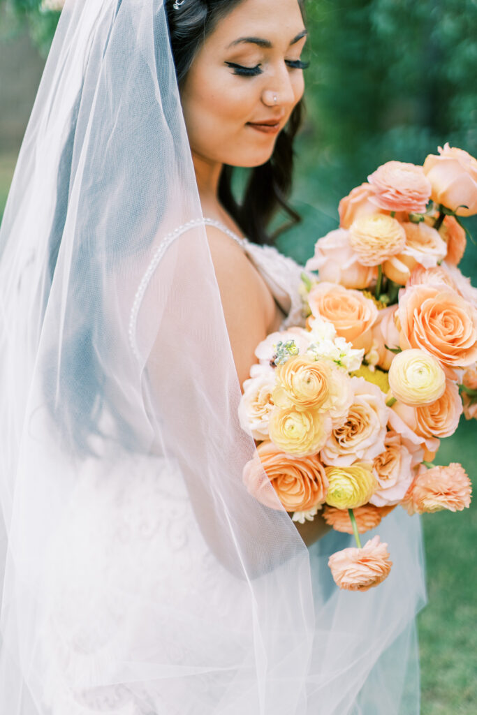 Lush peach and yellow bridal bouquet held by bride.