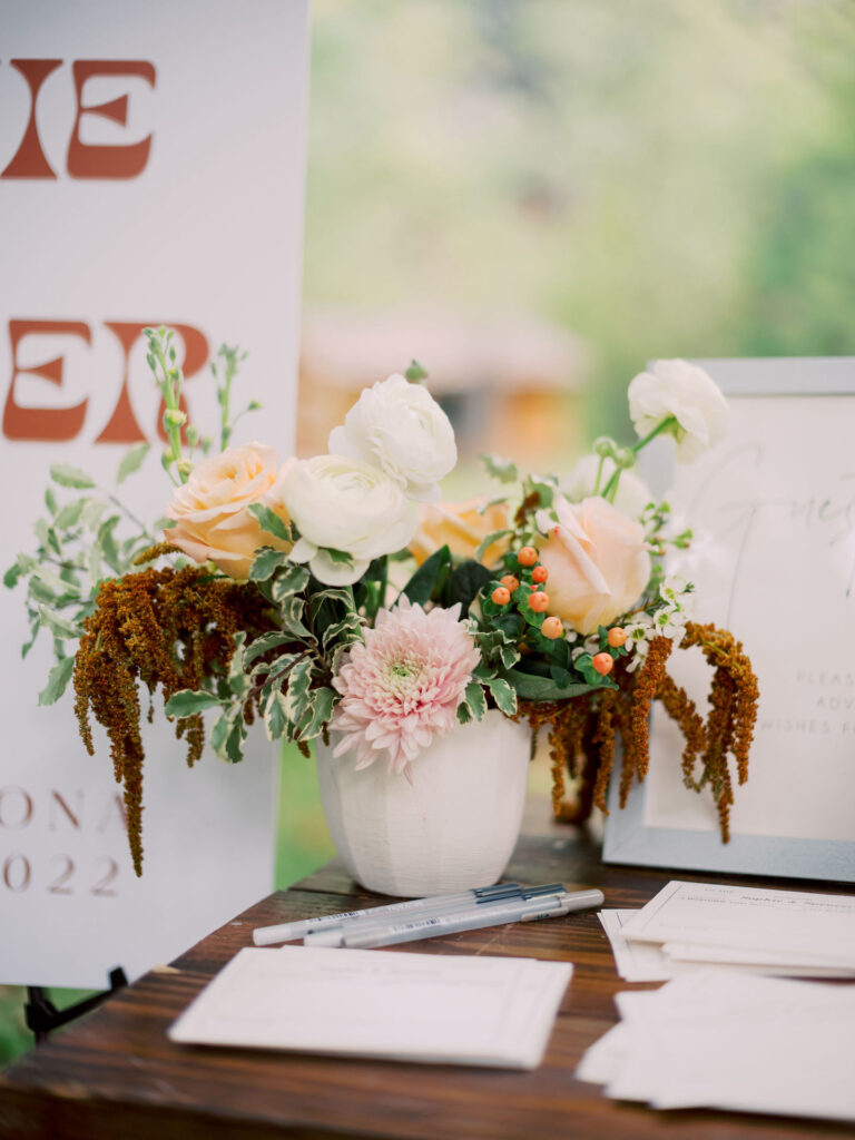 Wedding welcome table floral arrangements with brown, white, peach colors.