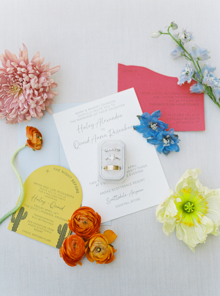 Wedding invitation with rings and floral details.