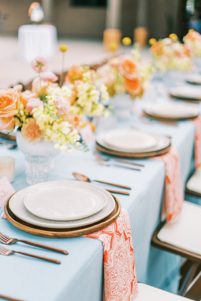 Long reception table with place settings and floral centerpieces.