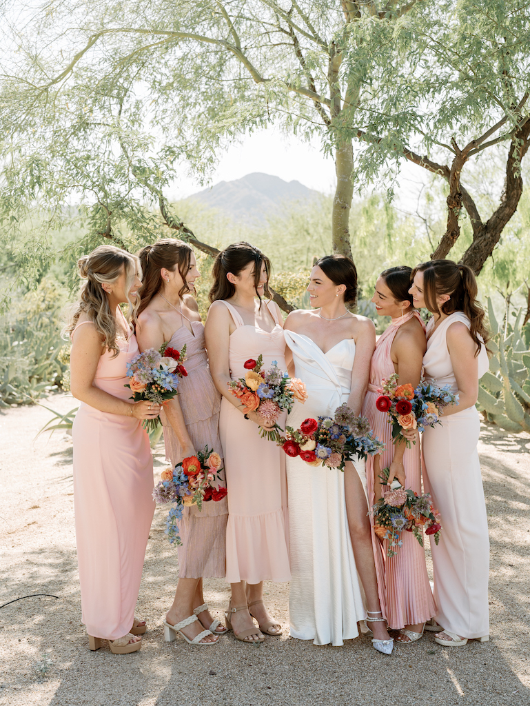 Bride standing with bridesmaids in desert landscape.