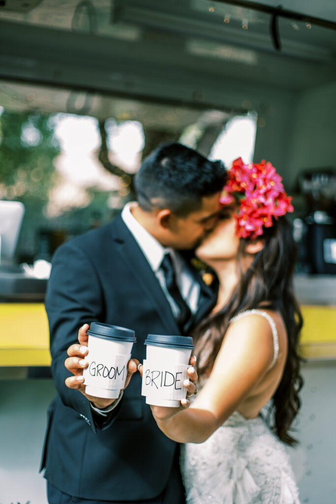 Bride and groom kissing in background holding out to-go coffee cups with "Bride" and "Groom" written on each.