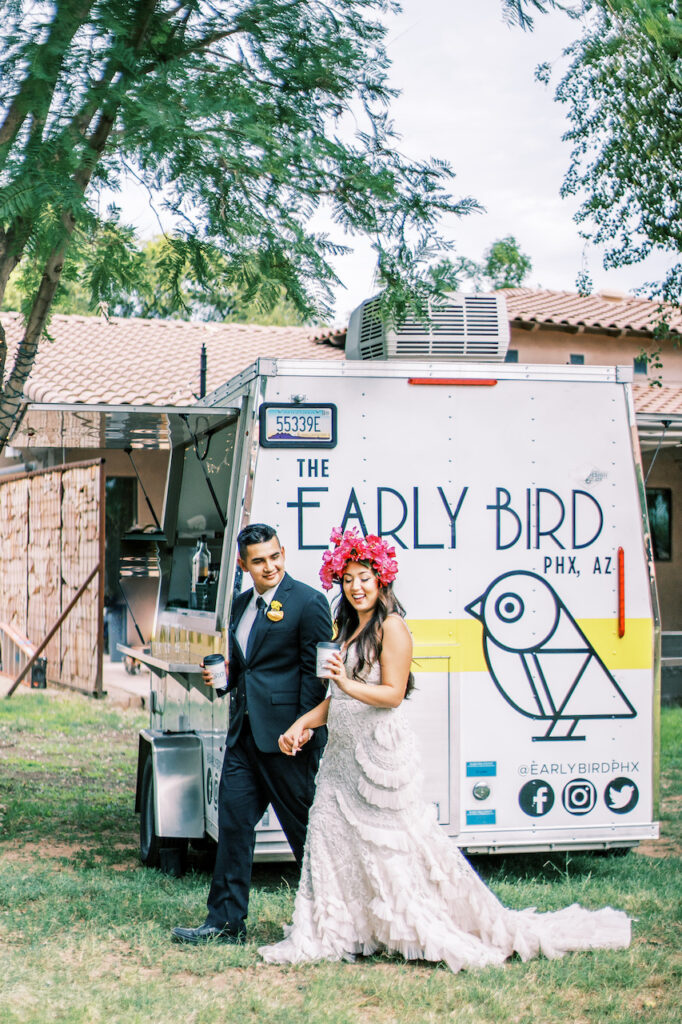 Bride and groom holding hands walking in front of The Early Bird food truck.
