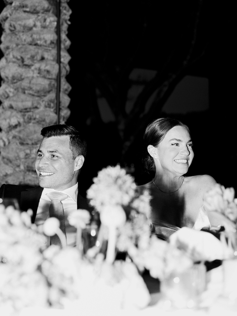 Black and white photo of bride and groom smiling, looking off to side.