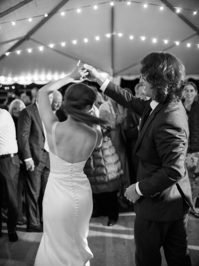 Bride and groom dancing during wedding reception under tent.