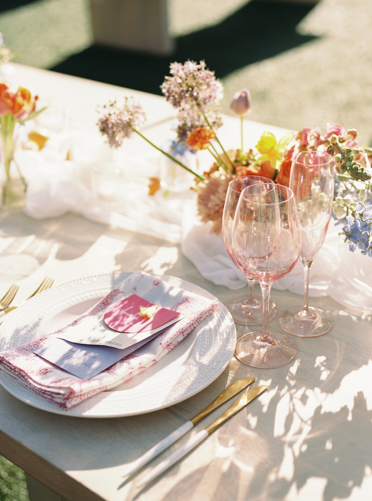 Place setting for wedding reception with floral centerpieces and pink details.