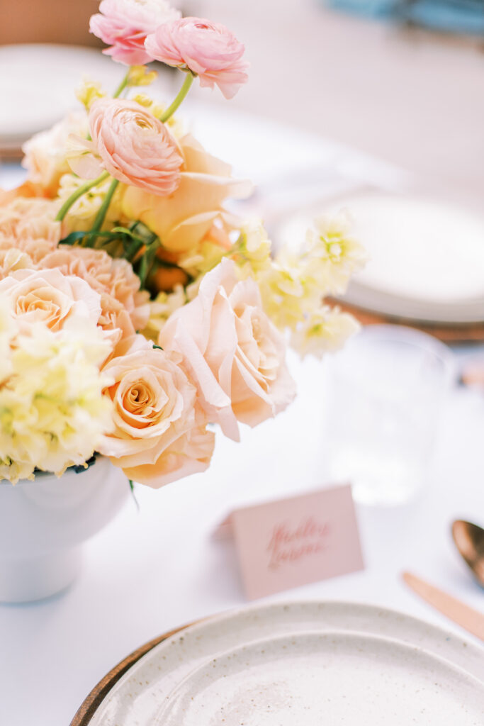 Reception centerpiece of pink and yellow flowers in white vase.