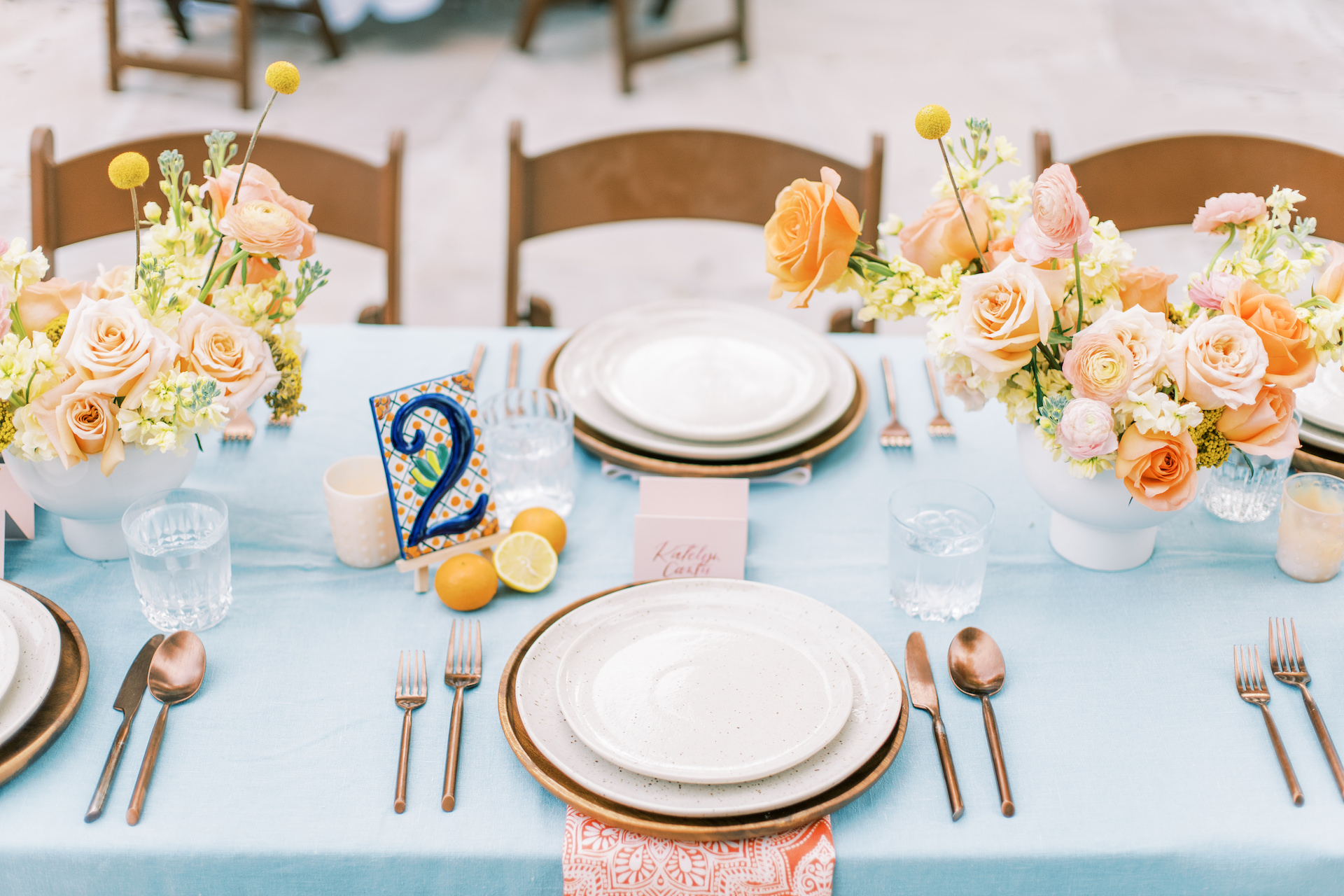 Wedding reception table with place settings, floral centerpieces and table number.