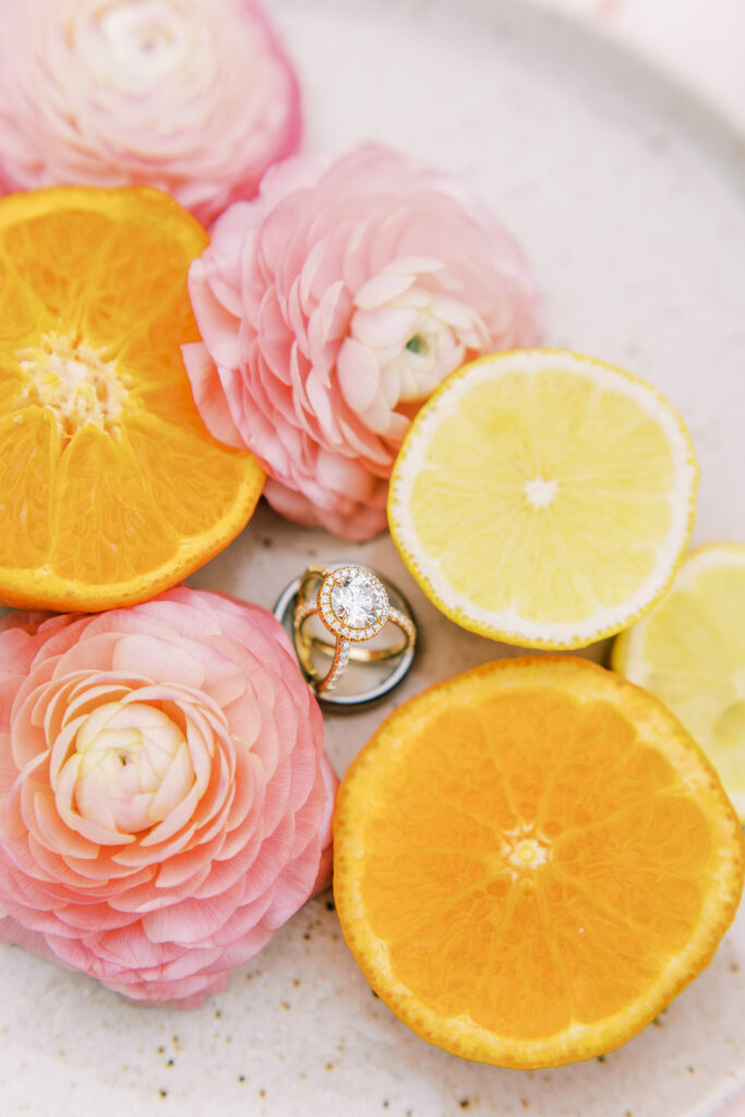 Wedding ring details shot with lemons, oranges and pink flowers.