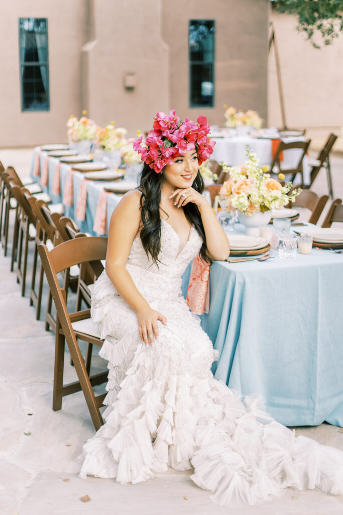 Bride with bougainvillea flower crown, sitting down at table.