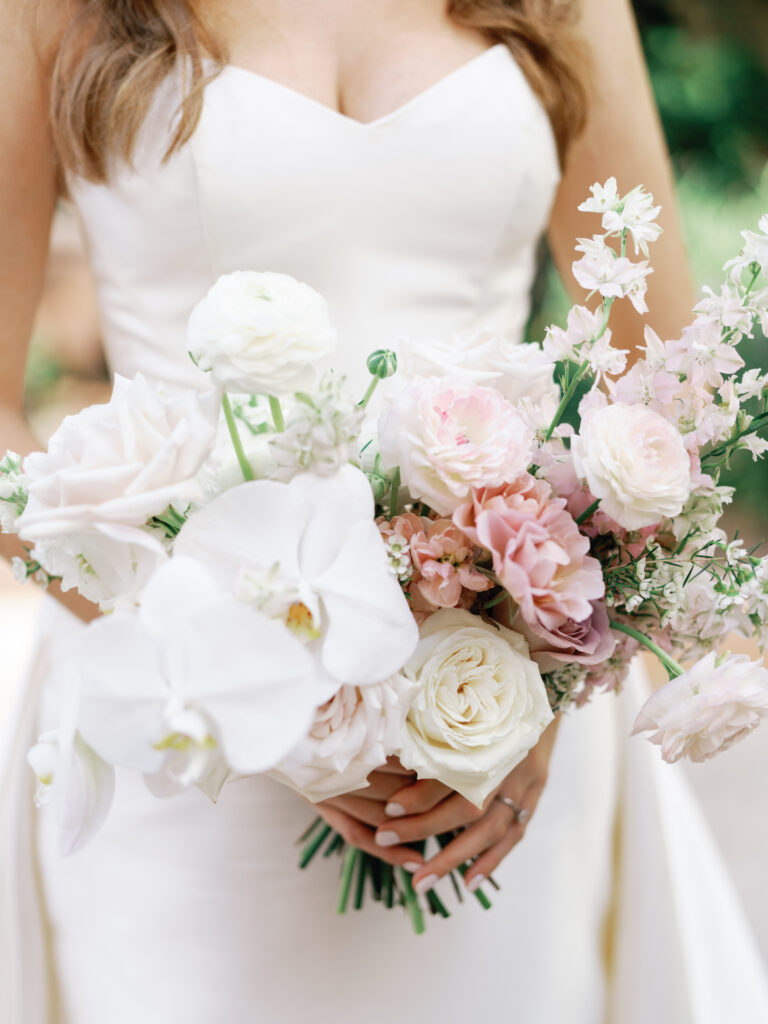 Bridal bouquet of white and blush pink flowers including orchids.