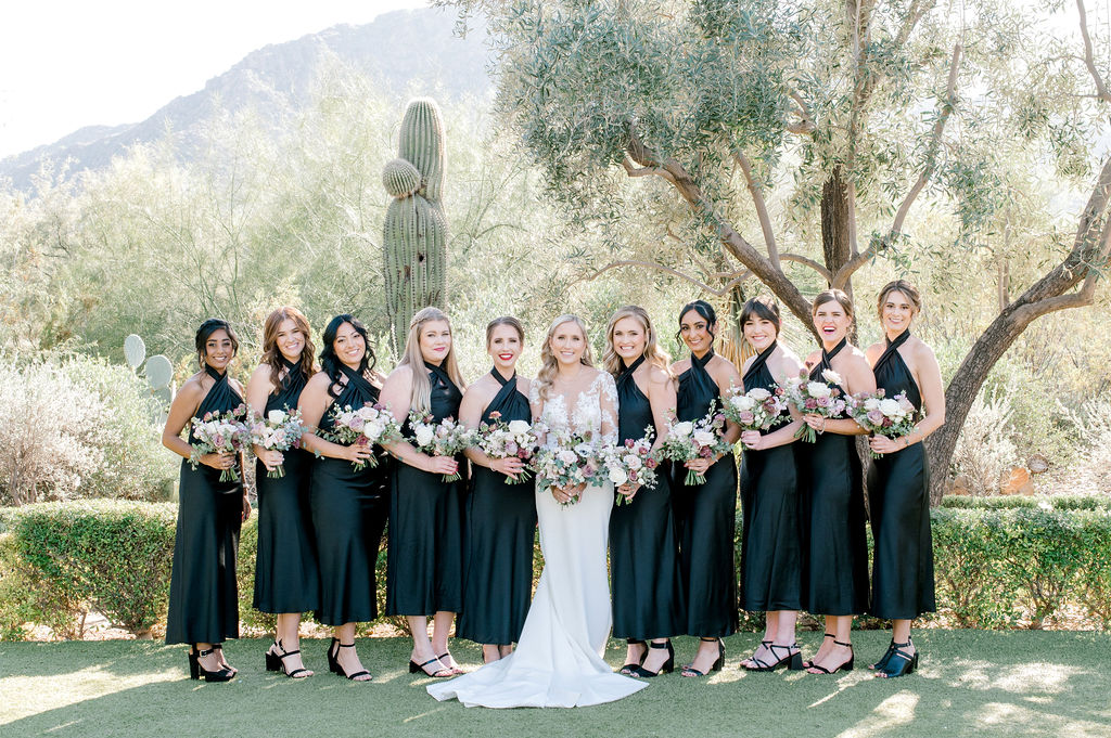 Bride standing with bridesmaids in a line wearing dark green dresses.